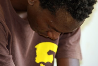一个非洲裔美国人坐着祈祷时低头看着他的手。
